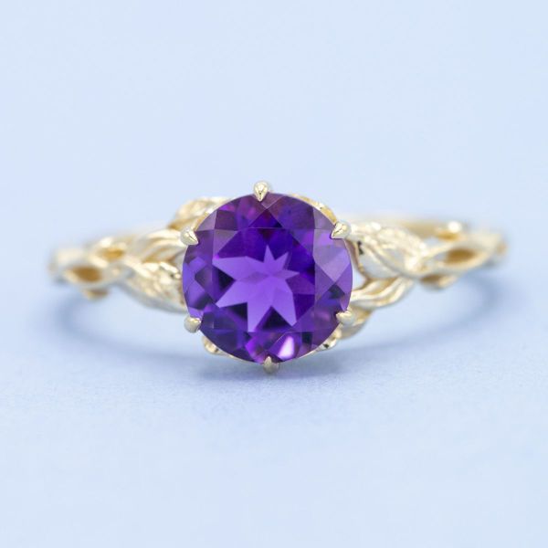 A brilliant round amethyst glitters in vivid purple on this yellow gold engagement ring.