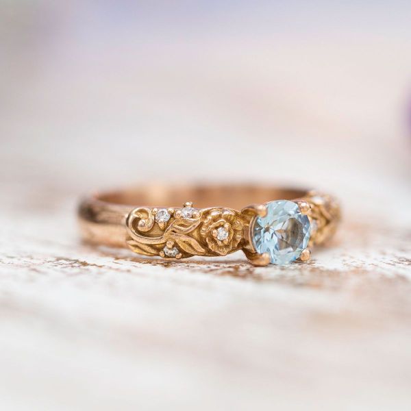 This sky blue topaz rose engagement ring includes diamond accents growing around the band.
