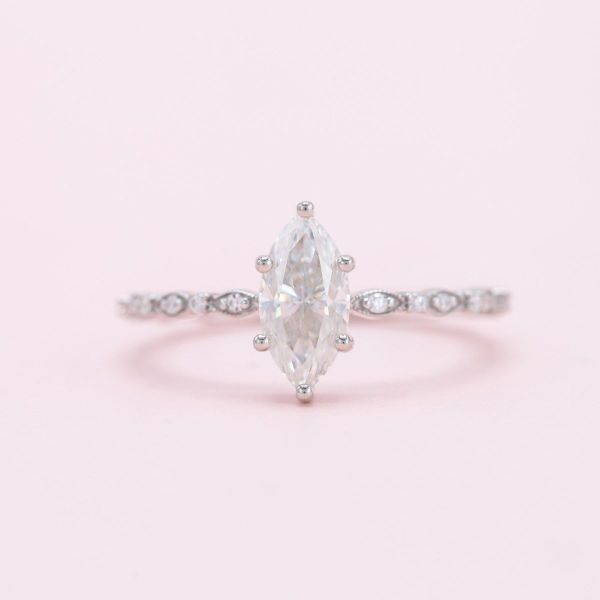 Pavé-set moissanites sit in eye-like settings along the white gold band of this marquise cut moissanite engagement ring.