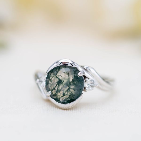 Unique, modern engagement ring in white gold with a round moss agate center stone.
