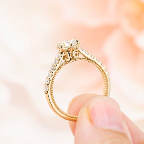 Moissanite accents line the arches holding the moissanite center stone above the couple’s initials in this cathedral set engagement ring.