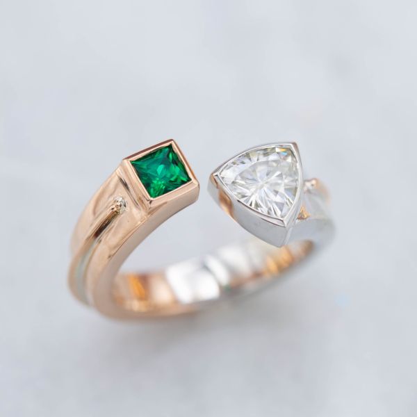 A cuff-style ring, with bold, with contrasting gem shapes and colors set on a mixed-metal gold band.