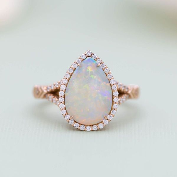 This opal engagement ring has diamond accents throughout its halo and split-shank band.