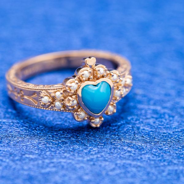 Inspired by Victorian design, this turquoise ring sets pearls in a heart-shaped halo around the center stone.