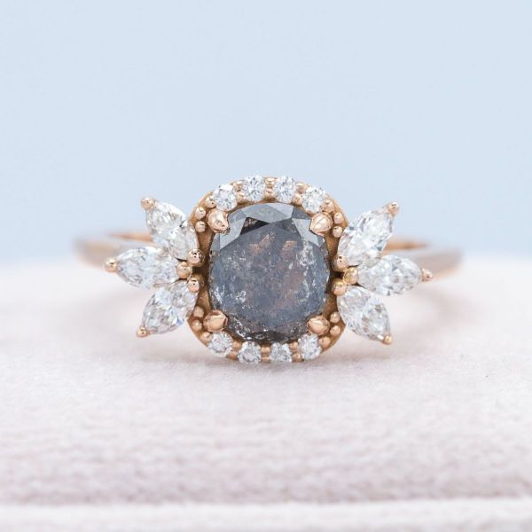 A salt and pepper cushion cut diamond is framed by a uniquely designed halo.
