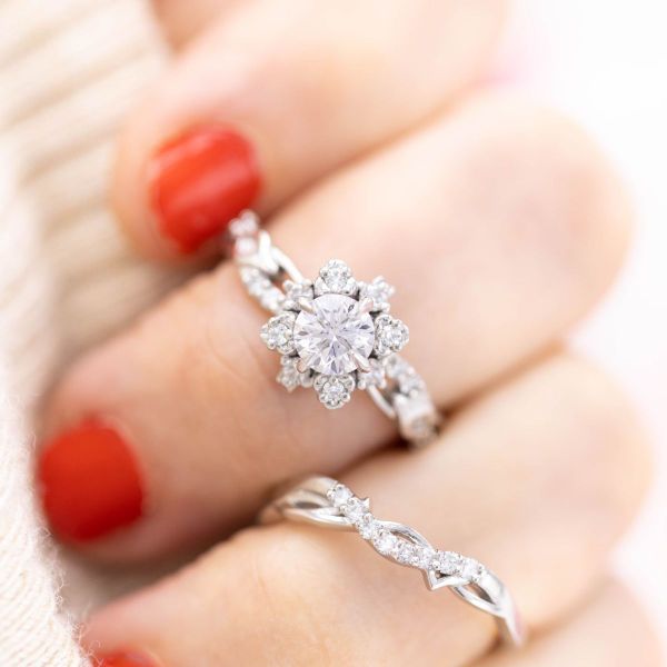 A snowfall of diamonds gently drifted onto this bridal set, as a winter flower emerges from underneath the engagement ring as thorns poke out from under the matching wedding band.