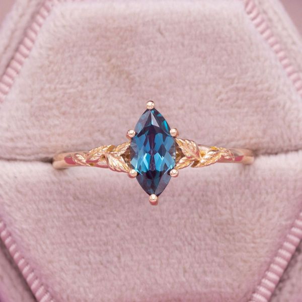 A bright blue marquise cut alexandrite is the solitaire stone in this nature inspired engagement ring.