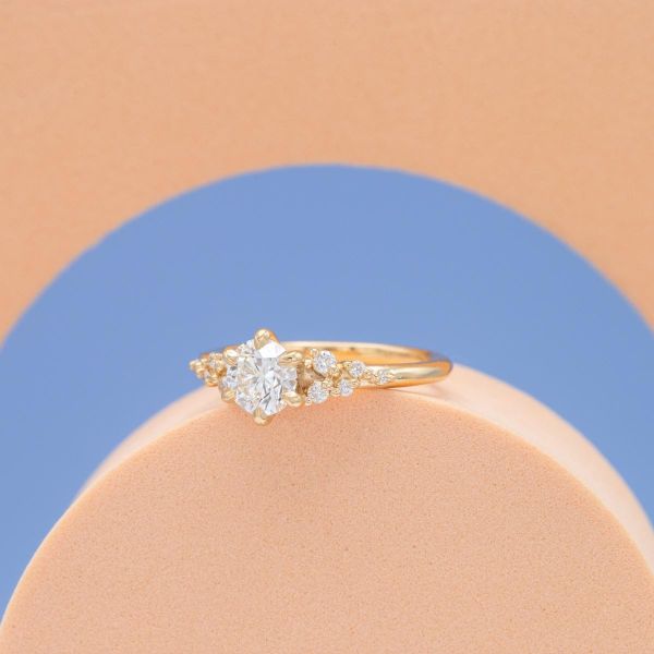 Multiple tiny diamonds float around the center stone on this yellow gold band.