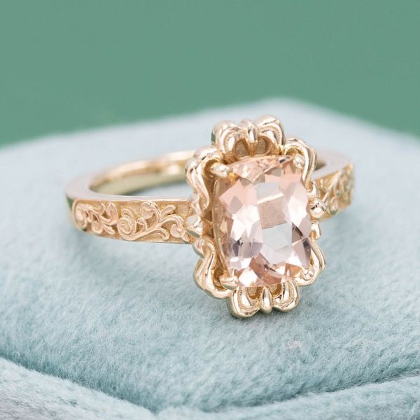 A stunning morganite stone is set in a vintage style frame with an elaborately decorated band.