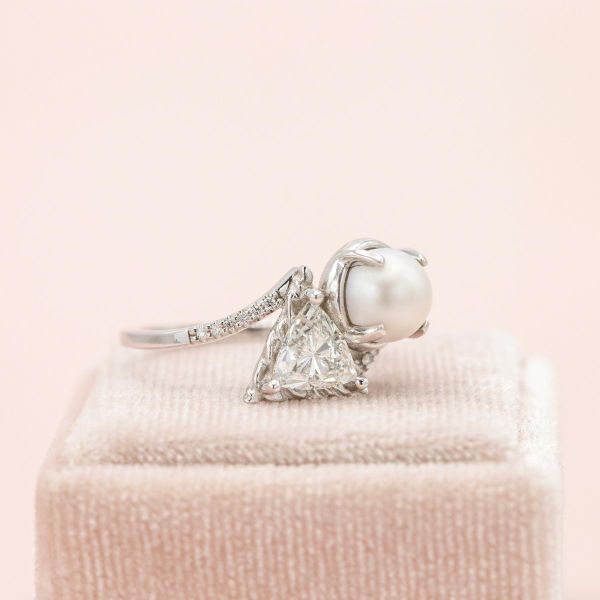 This diamond studded, white gold band has both a diamond and pearl at its center.