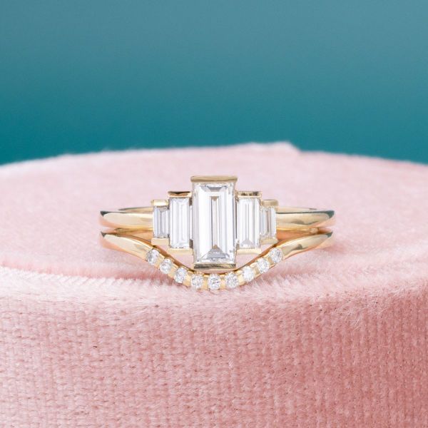 This bridal set features a five-stone engagement ring with an array of graduated baguette cut diamonds and a curved wedding band.