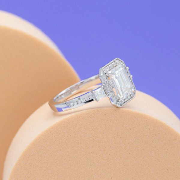 A haloed emerald cut moissanite gives vintage vibes in this engagement ring while the channel-set moissanite white gold band pulls this ring into modern times.