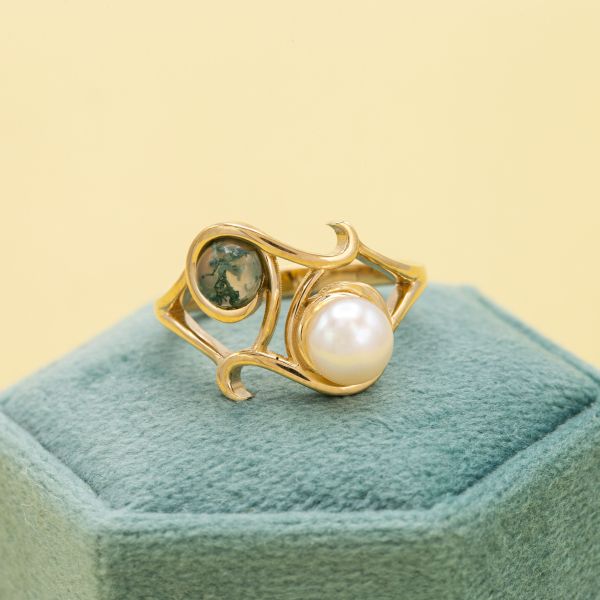 这款独特的双石戒指将珍珠和青苔玛瑙搭配在开放式的雕塑曲线设计中。