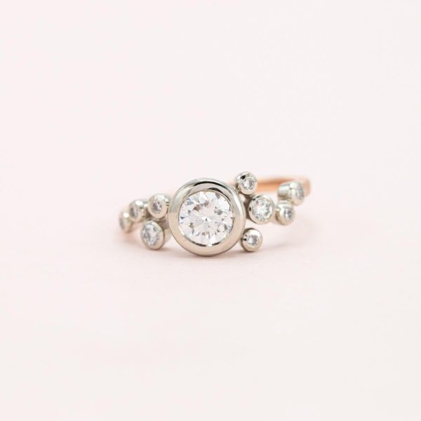 A bubbly engagement ring with bezel set diamonds in a scattered arrangement.