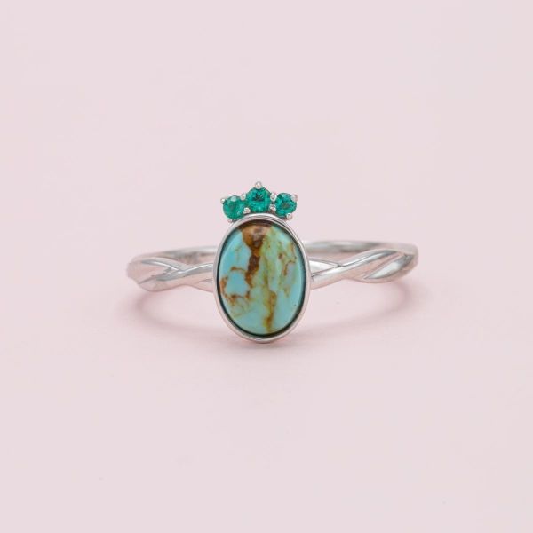 A tiara-like arrangement of emeralds accents this ring's Kingman turquoise center stone.