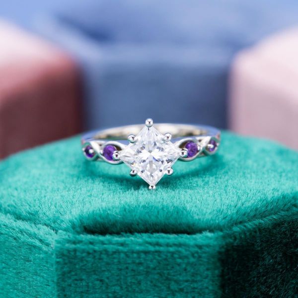 Amethysts flank the band of the princess cut moissanite in this engagement ring.