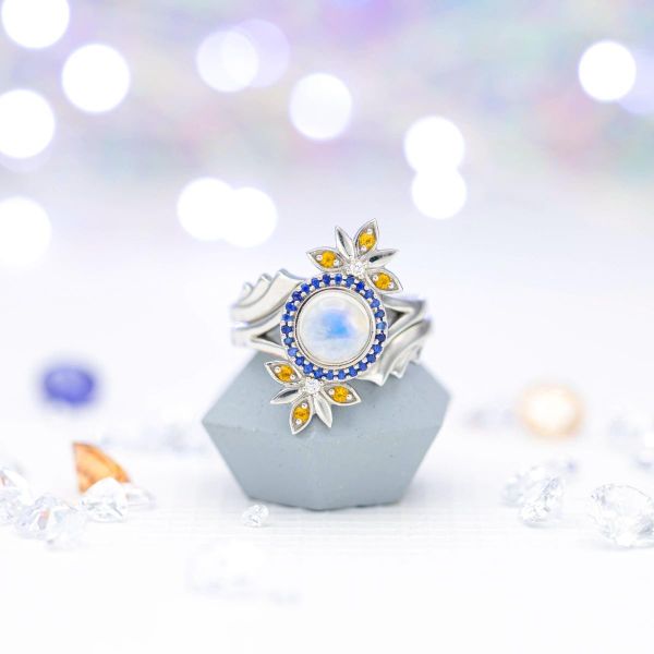 以月食为灵感的新娘套装，由蓝宝石和“耀斑”的黄水晶镶成月光石，搭配装饰风格的环绕式袖口结婚戒指。