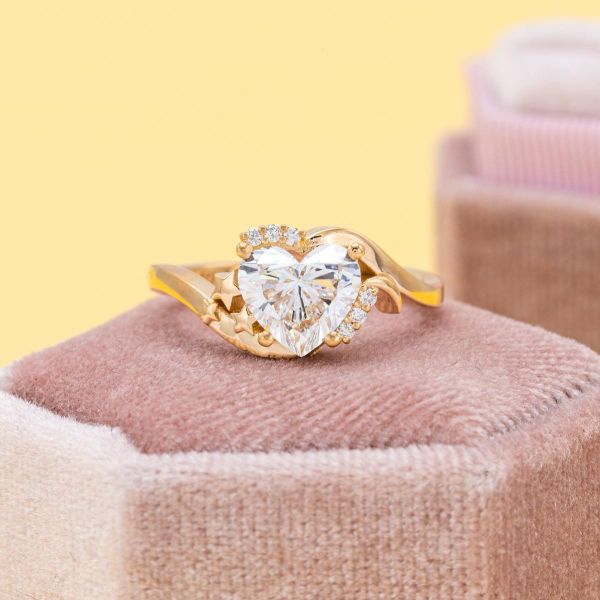 A heart shaped lab diamond sits in the center of this yellow gold engagement ring.