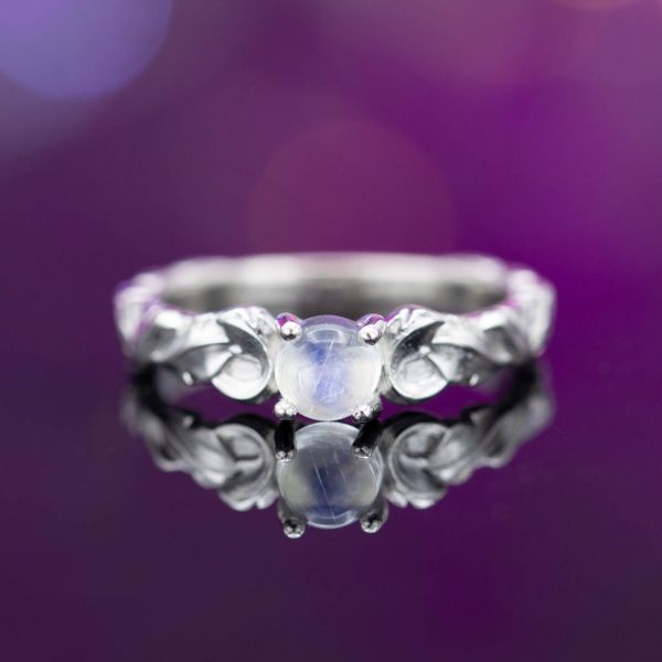 这枚戒指的中心宝石是一颗光滑的月长石，戒指带的特点是有角度的运动，形成对比。