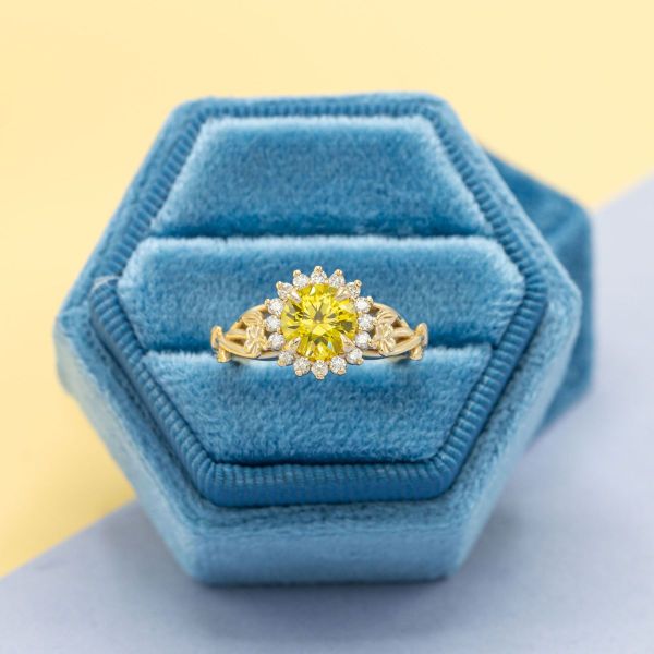 A round yellow sapphire in a yellow gold setting with diamond halo to look like a sunflower.