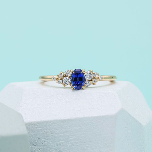 Oval blue sapphire with diamond accents and a yellow gold setting.