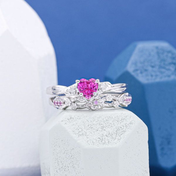 A white gold bridal set featuring a pink, heart cut sapphire.