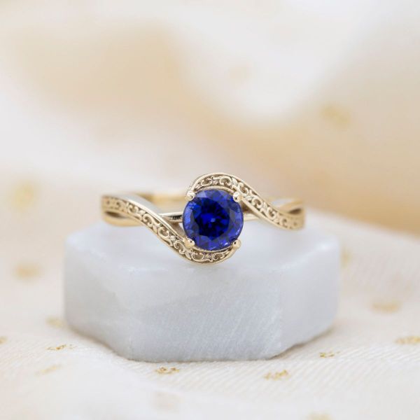 Musical notes grace the side profile of this lab created sapphire engagement ring.