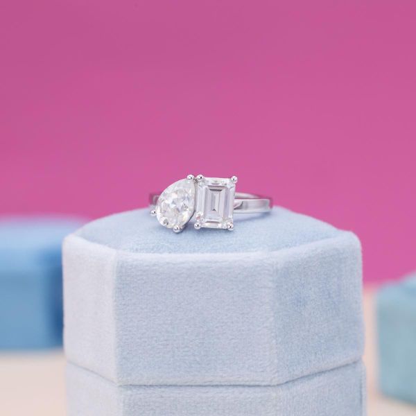 Emerald and pear shaped moissanites are the center of this toi et moi engagement ring.