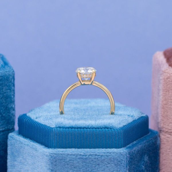 A hidden halo of diamond accents is tucked between the yellow gold prongs holding this engagement ring’s solitaire diamond.