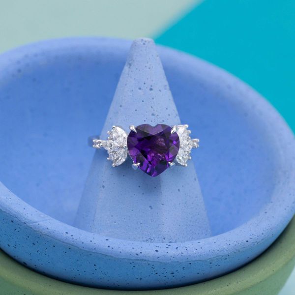 A heart cut amethyst sits at the center of this white gold engagement ring flanked by diamond accents