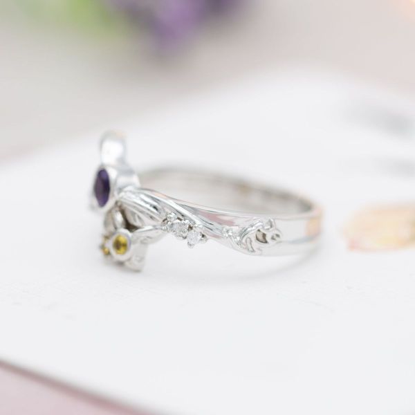 This ring pops with Legend of Zelda inspired fairy designs centered by a purple amethyst and yellow sapphire.