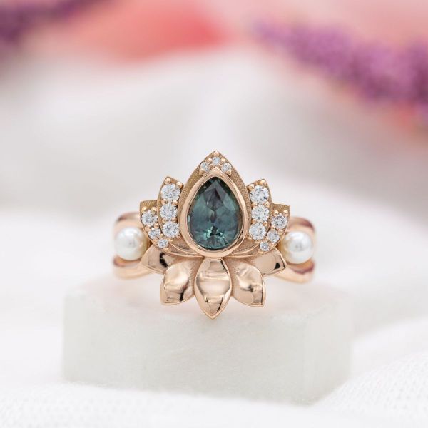 A pear cut teal sapphire in a lotus inspired yellow gold setting.