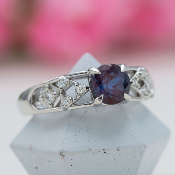 A piercing purple alexandrite stone centers this white gold engagement ring which features four Triforce inspired designs.