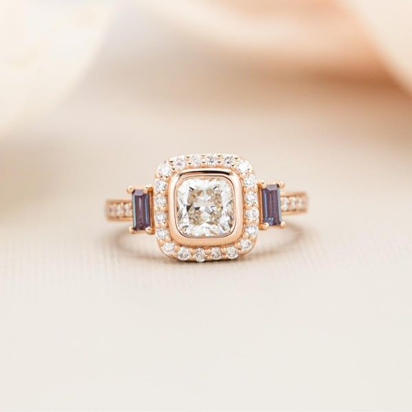 A halo of accents line the cushion cut lab diamond in the center of this engagement ring.