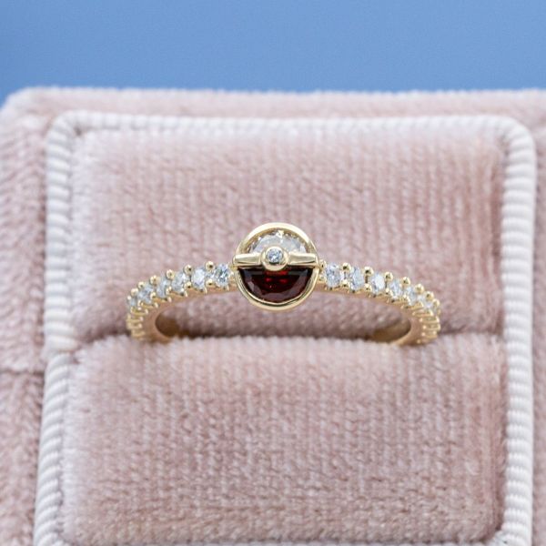 Garnet and moissanite sit at the center of this Pokeball inspired ring.