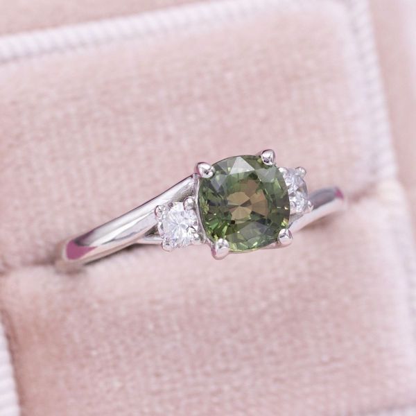 This engagement ring features a natural alexandrite, appearing a light green in this lighting.