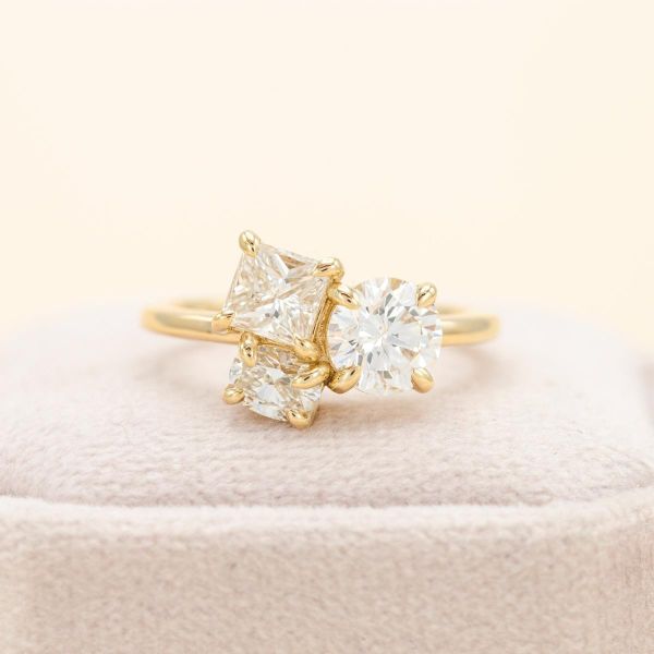 Three diamonds sparkle on this yellow gold band, creating an all white cluster.