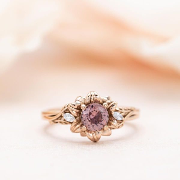 This rose gold lotus ring sports a burgundy sapphire at its center.