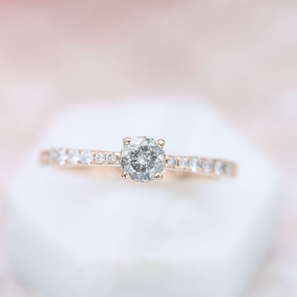 Uniform speckling in this diamond gives it a cool, steely appearance, contrasting beautifully with the tapered diamond pave along the ring's band.
