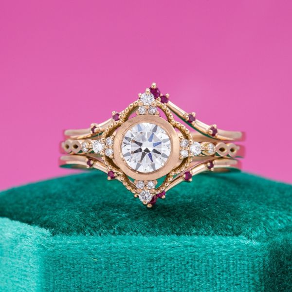 Diamond and ruby accents dot the edges of this yellow gold engagement ring with a lab diamond center stone.