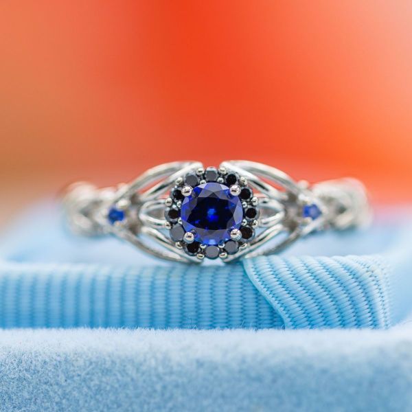 Blue sapphire center stone, mozambique garnet, and sapphire accents give this ring all the bling.