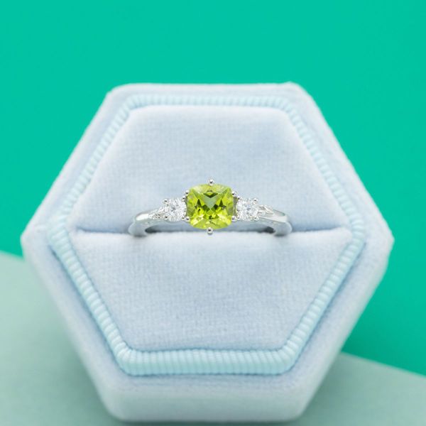 A peridot center stone with diamond accents in white gold.