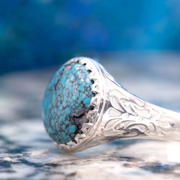 This bold statement ring echoes the beautiful black veining of the turquoise center stone with intricate engraving on the ring's shoulders.
