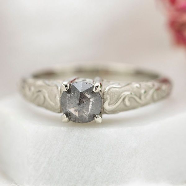 This otherworldly engagement ring features a rose cut salt and pepper diamond at its center, with a white gold band.