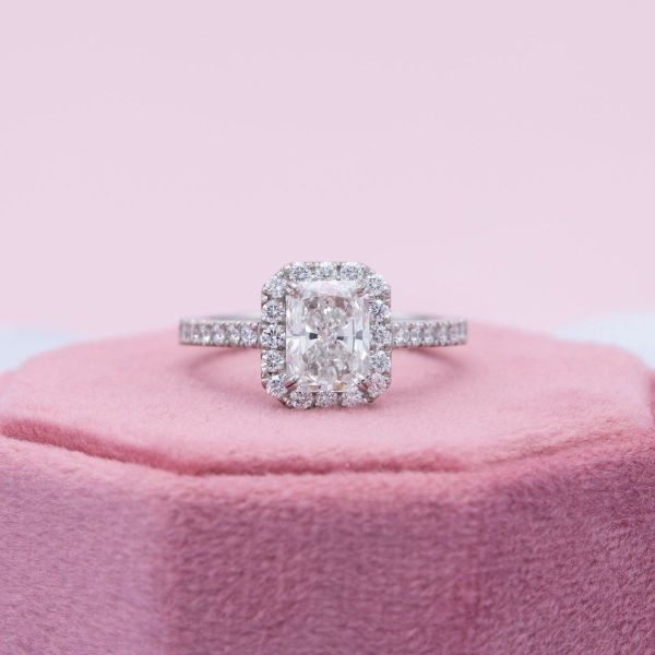 Pavé set diamond arches hold up a radiant cut diamond and diamond halo in this cathedral setting engagement ring.