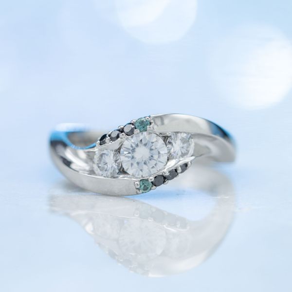 现代版的三块钻石订婚戒指，将钻石雕刻在一个宽而弯曲的环上。