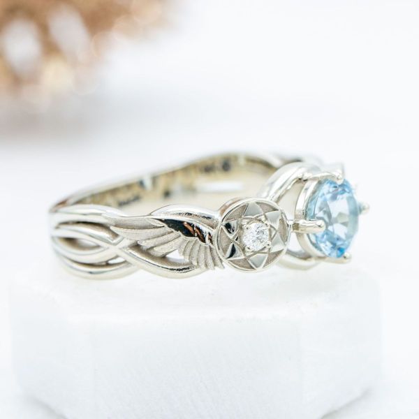 An aquamarine takes center stage next to sharingan eye-like detailing in this Naruto inspired engagement ring.