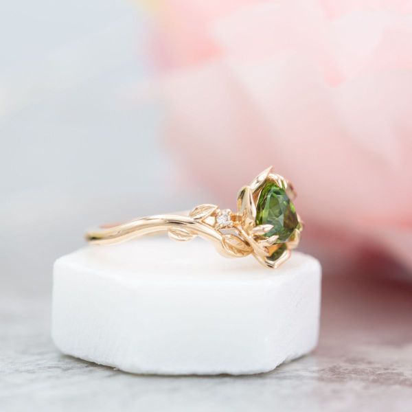 A green tourmaline trillion blooms at the center of a rose gold petal setting in this floral engagement ring.