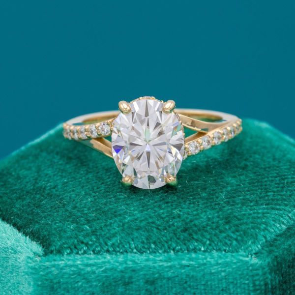 A split shank yellow gold band holds this oval moissanite.
