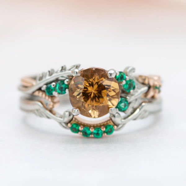 Rose gold flowers and leaves adorn the white gold band of this autumn-inspired ring that features imperial topaz and emerald accent stones.
